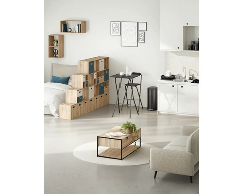 Ljust vardagsrum med hyllsystem, bord, stol, soffa och pentry.