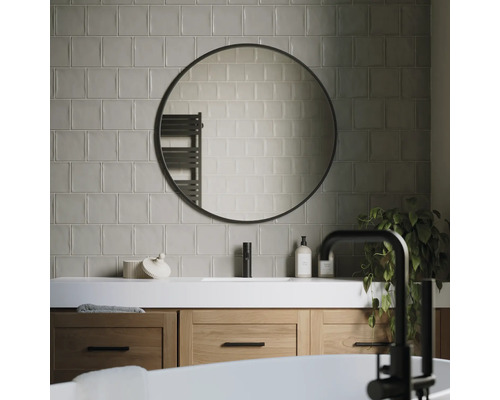 Modernt badrum med tvättställ, rund spegel och kakel