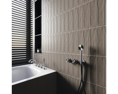 Modernt badrum med badkar, armaturer, hyllor och avlånga väggplattor