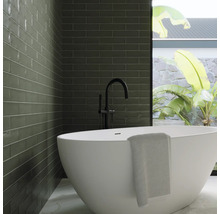 Modernt badrum med grönt kakel, fristående badkar och svart armatur