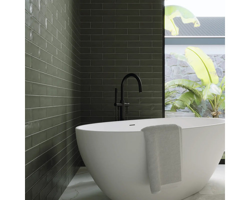 Modernt badrum med grönt kakel, fristående badkar och svart armatur