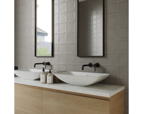 Modernt badrum med dubbla handfat, kranar, speglar och grå väggplattor