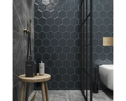 Badrum med sexkantiga väggplattor, dusch, toalett och träpall