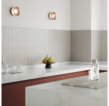 Köksscen med vägglampor, kakel och köksredskap på bänkskivan.