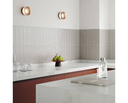 Köksscen med vägglampor, kakel och köksredskap på bänkskivan.