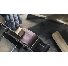 Närbild av en bandslipmaskin som bearbetar ett arbetsstycke