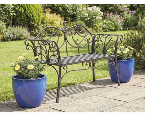 Dekorerad trädgårdsbänk i metall med blomkrukor på en trädgårdsterrass