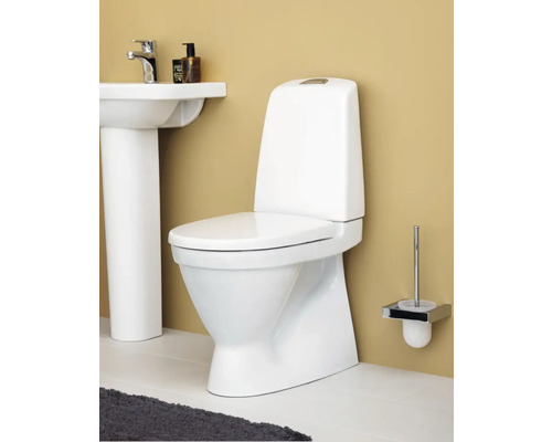 Vit golvstående toalett med cistern i badrumsmiljö