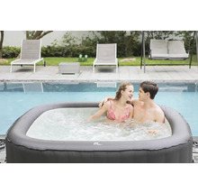 Scen med ett par i en uppblåsbar jacuzzi bredvid en pool, omgiven av solstolar och en gunga