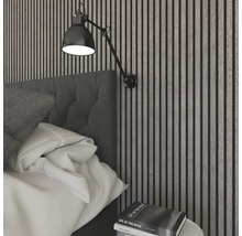 Modernt, ljust sovrum med akustikpaneler av träribbor, en stoppad sänggavel i tyg och en vägglampa i metall.