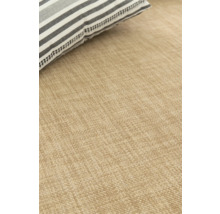 Detaljvy av en beige matta med en randig kudde.