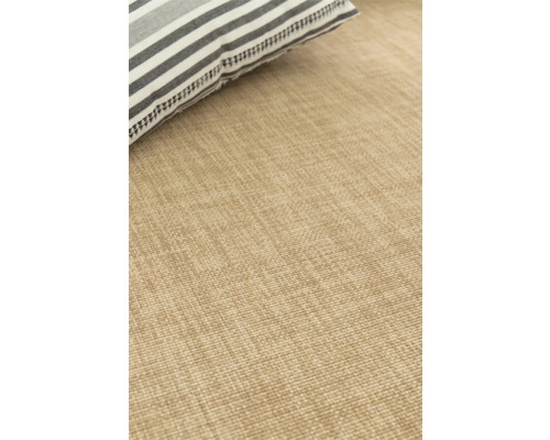 Detaljvy av en beige matta med en randig kudde.