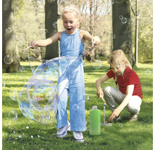 Två barn leker i parken med ett såpbubbelset och skapar stora såpbubblor.