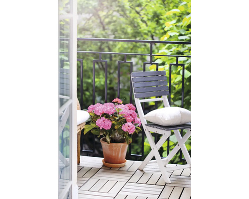 Balkong med stolar, kudde, blommor och terrassplattor