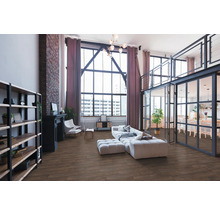 Rymligt vardagsrum i industriell loftstil med golv i trädekor, stora fönster, tegelvägg och moderna möbler.