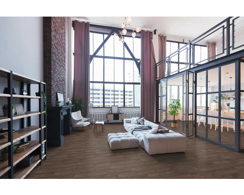 Rymligt vardagsrum i industriell loftstil med golv i trädekor, stora fönster, tegelvägg och moderna möbler.