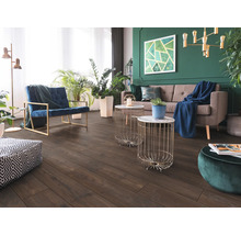 Vardagsrum med mörkt golv i trälook, grå soffa, blå fåtölj och grön vägg med inomhusväxter. Modern och ljus inredning.