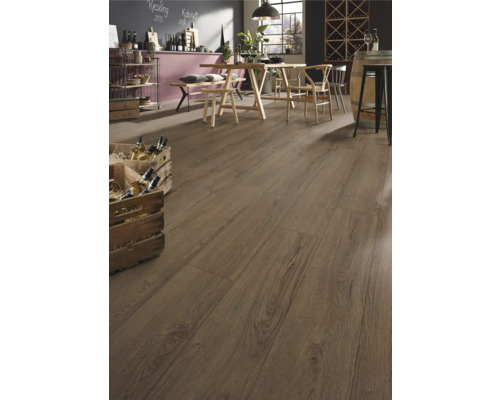 Rustikt laminatgolv i eklook i ett ljust, rymligt rum med träbord, stolar och vinlådor i lantlig stil.