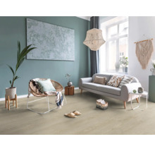 Ljust vardagsrum med golv i träoptik, grå soffa, korgfåtölj, stor taklampa och väggdekoration i boho-stil.