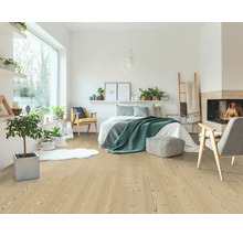 Ljust sovrum med laminatgolv i ljust träutseende, inrett med säng, fåtöljer, inomhusväxter och en mysig öppen spis.