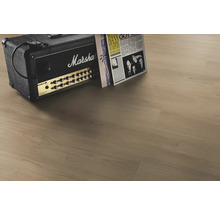 Laminatgolv i ljus eklook med autentisk träådring, kombinerat med en gitarrförstärkare med Marshall Logo och vinylskivor.