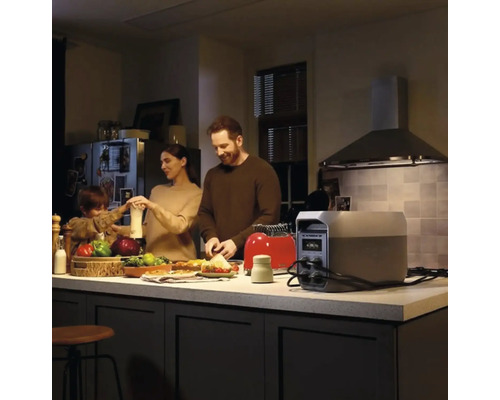 Bärbar kraftstation på en köksö som strömförsörjer en brödrost medan en familj lagar mat i ett modernt kök.