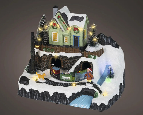 Julminiatyrlandskap med belyst hus, tåg, barn, hund och snötäckt bergsmiljö.