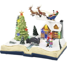 Juldekoration i form av en öppen bok med snöigt vinterlandskap, upplyst hus, julgran och jultomte i släde.
