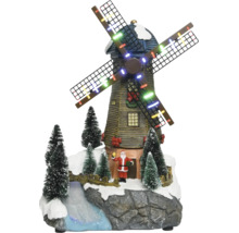 Juldekoration med en belyst väderkvarn, tomtefigur, snöklädda granar och en bäck på en klippbas.