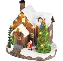 Julby miniatyr med ett snöigt hus, en belyst gran, en jultomtefigur och en ljusslinga.
