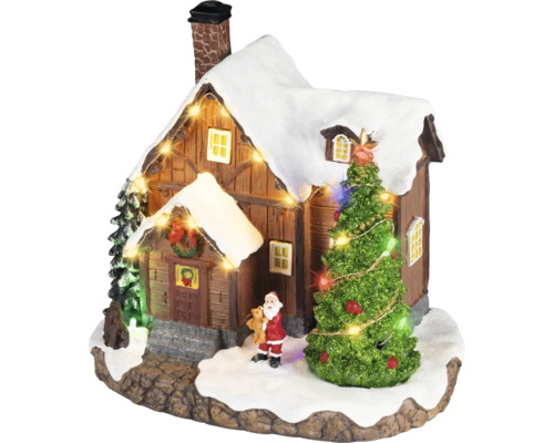 Julby miniatyr med ett snöigt hus, en belyst gran, en jultomtefigur och en ljusslinga.
