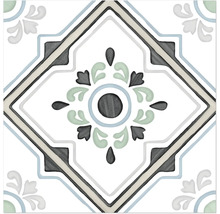 Dekorativ kakelplatta med symmetriskt ornamentalt mönster, centralt blommotiv och rutförmad bård.