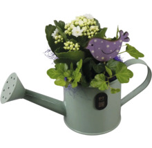 Blomsterarrangemang med vit våreld och grön murgröna i en dekorativ vattenkanna av metall med en lila fågelsticka.