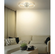 Modern LED-taklampa med flera ljusringar i ett ljust vardagsrum över en soffa.