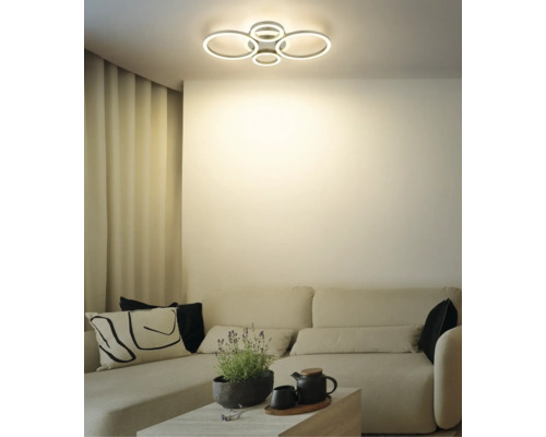 Modern LED-taklampa med flera ljusringar i ett ljust vardagsrum över en soffa.
