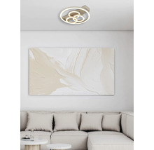 Modern LED-taklampa med fyra ringar i ett ljust vardagsrum ovanför en abstrakt tavla och en soffa.