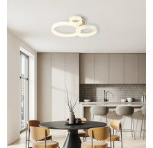 Modern LED-taklampa med tre sammankopplade ringar i ett ljust, minimalistiskt kök med matbord och barstolar.