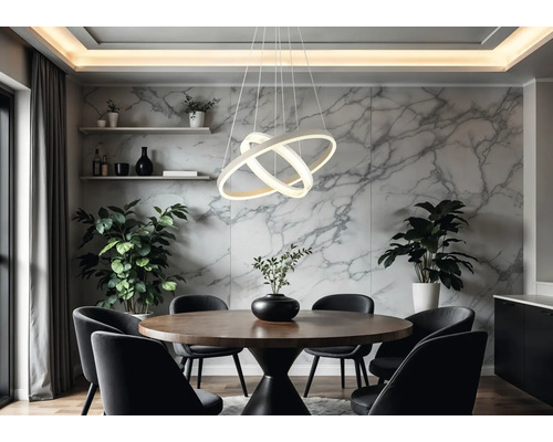 Modern LED-pendellampa med tre sammanflätade ringar över ett runt matbord i trä i ett ljust rum med väggar i marmorlook.