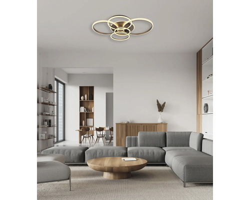 Modern LED-taklampa med flera ringar i ett ljust, organiserat vardagsrum med grå soffa och trämöbler.