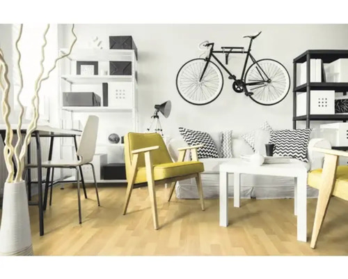 Modernt ljust vardagsrum med gul fåtölj, vit soffa, soffbord, cykelväggfäste och ljust trägolv.