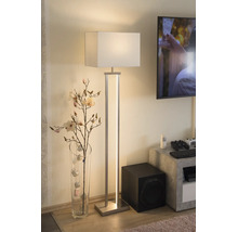 Modern golvlampa med vit textilskärm och integrerad LED-list i ett vardagsrum bredvid en glasvas med grenar.