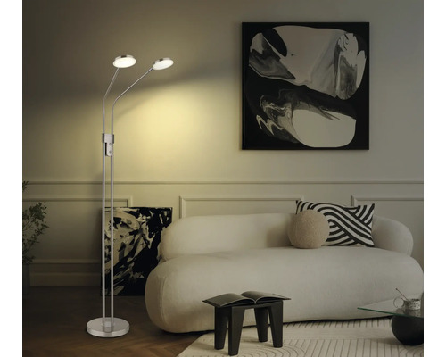 Tvålågig LED-golvlampa i metall i ett ljust vardagsrum med vit soffa och abstrakta tavlor.