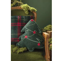 Prydnadskudde i form av en julgran i grönt strukturerat tyg med broderier och röda ornament på en fåtölj med mossa.