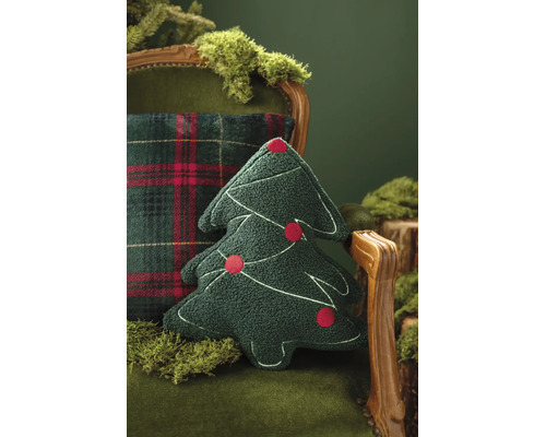 Prydnadskudde i form av en julgran i grönt strukturerat tyg med broderier och röda ornament på en fåtölj med mossa.