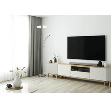 Modernt, ljust vardagsrum med en golvlampa i metall med läsarm bredvid en mediabänk med TV.