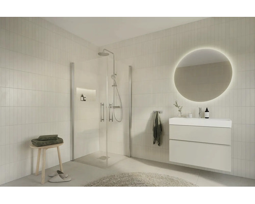 Modern, ljust badrum med en duschkabin i glas, kommod med tvättställ och en rund bakgrundsbelyst LED-spegel.