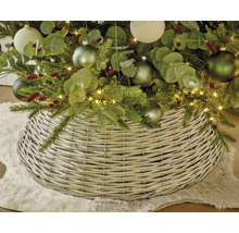Julgransfotsskydd av flätat pilträ under en klädd julgran på en matta av fuskpäls.