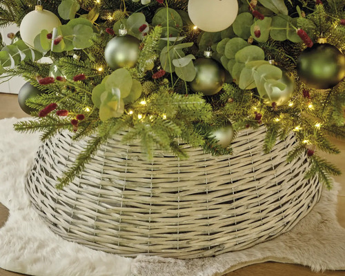 Julgransfotsskydd av flätat pilträ under en klädd julgran på en matta av fuskpäls.
