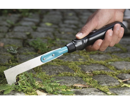 Hand med fogskrapa som används för ogräsbekämpning