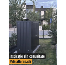 Modernt trädgårdsskjul i metall i mörkgrått på en gräsmatta i en trädgård framför ett hus.